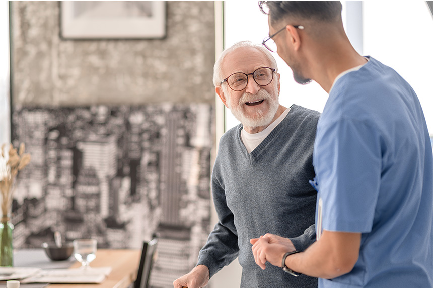 An older man smiles at a male healthcare professional.